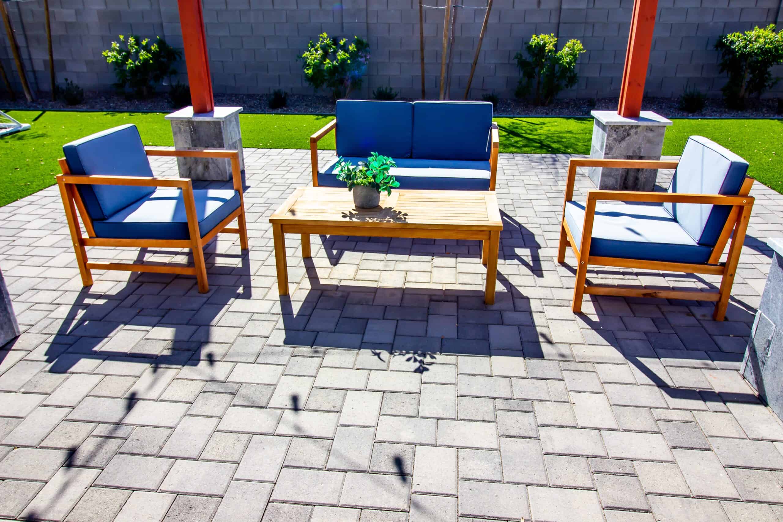 a stone paver patio under a gazebo with blue and oak outdoor furniture