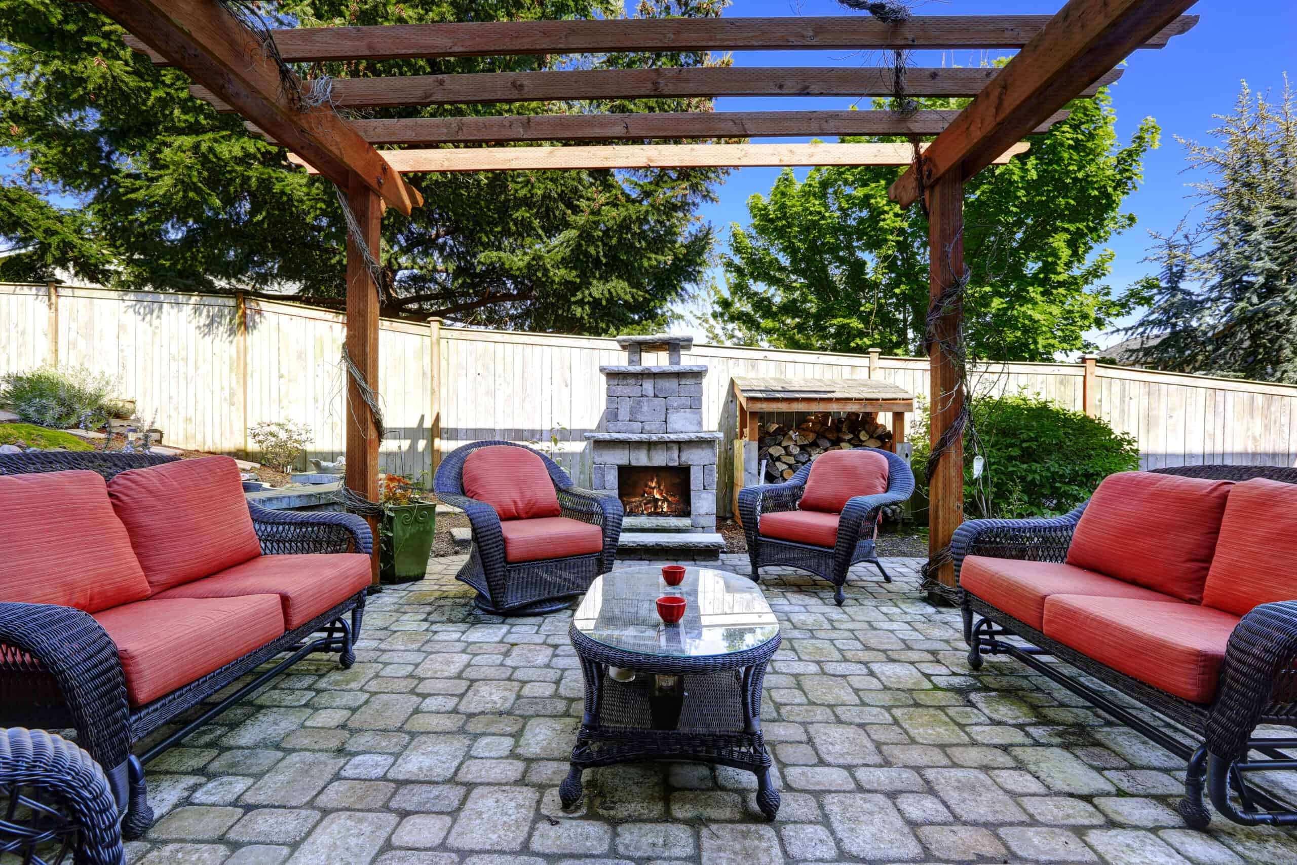 an outdoor living space with red and black wicker furniture and a firepit